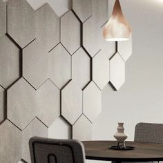 a dining room table and chairs in front of a wall with hexagonal tiles