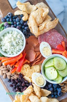 a platter filled with crackers, grapes, cucumbers and other snacks