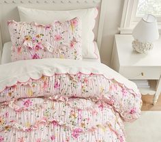 a white bed with pink and yellow flowers on it