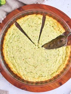 an overhead view of a quiche on a wooden platter with a serving utensil