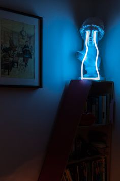 a blue light is shining on a shelf in a room with bookshelves and pictures