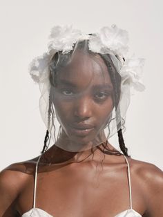 a woman in a white dress with flowers on her head