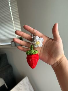 a hand holding a tiny crocheted strawberry keychain