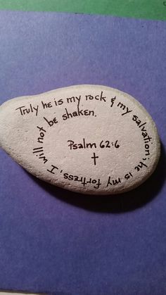 a rock with writing on it sitting on top of a purple table next to a pen