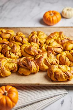 there are many small pastries on the table next to pumpkins and oranges