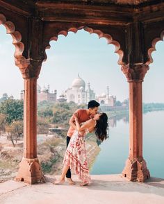 two people sitting on the edge of a building looking out over a body of water