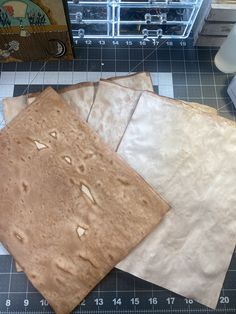 three pieces of brown paper sitting on top of a cutting board next to a ruler