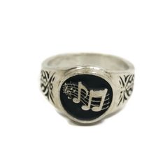 a signet ring with musical notes and trebles on the band, set in silver