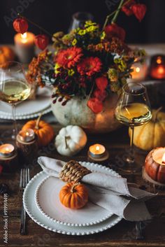 the table is set with candles, plates and pumpkins