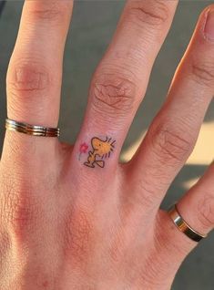 a person's hand with a small cat tattoo on the middle finger and an arrow