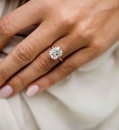 a close up of a person's hand with a diamond ring on their finger