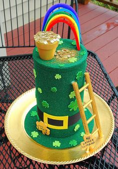 there is a green cake with gold decorations on the top and a ladder to it