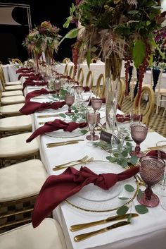 the table is set with many place settings and flowers in vases on each side