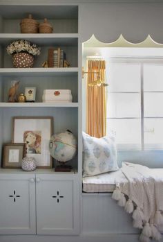 a window seat in a room next to a shelf with pictures and other items on it