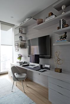 a living room with a large flat screen tv mounted to the wall next to a white chair