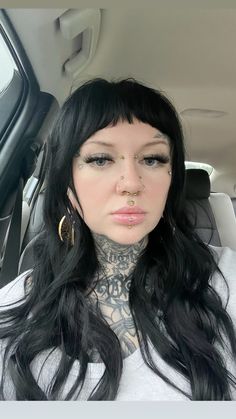 a woman with black hair and piercings sitting in a car