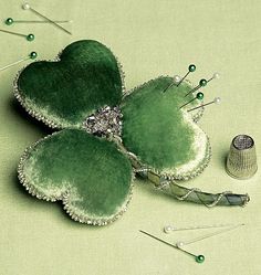 three green flowers with pins and needles on a table