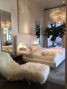 a bedroom with a bed, mirror and chandelier