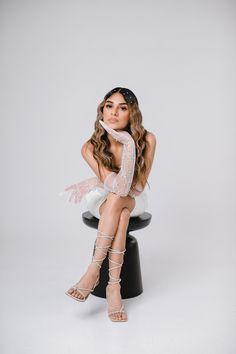 a woman sitting on top of a stool with her legs crossed and wearing high heels