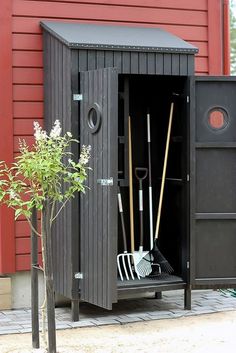 an outdoor storage shed with shovels, rakes and a potted plant in it