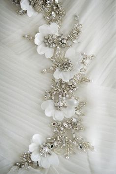 a white wedding dress with flowers and pearls on the waistline is seen in this close up photo