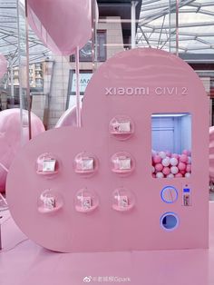 a pink heart shaped machine with lots of balloons in the back and on display behind it