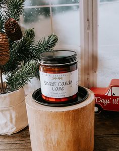 a candle sitting on top of a wooden table next to a christmas tree and window