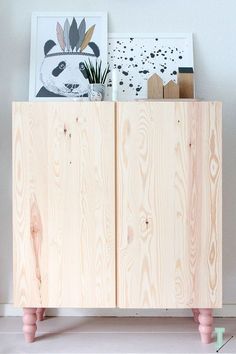 a wooden cabinet sitting on top of a white floor next to pictures and planters