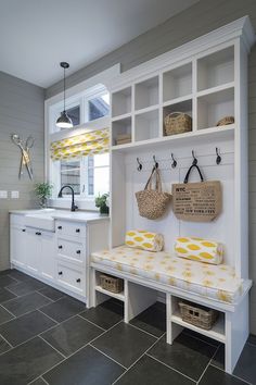 a kitchen with white cabinets and yellow cushions on the bench in front of the sink