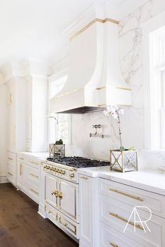 a kitchen with white cabinets and gold trimmings on the stove top, along with marble counter tops