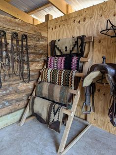 a horse stable with saddles and rugs hanging on the wall