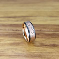 a wedding band with two black and gold rings on top of a wooden table in front of a wood surface