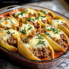 a casserole dish filled with stuffed shells and meat, garnished with parsley