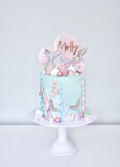 there is a cake with mermaid decorations on the top and under it's name