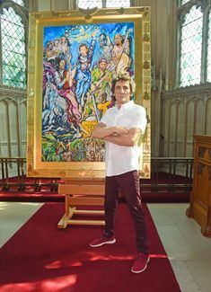 a man standing in front of a large painting on the side of a church wall