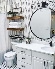 a bathroom with black and white wallpaper, a round mirror over the sink and shelves above the toilet