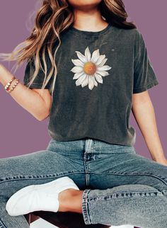 Elevate your style with our Large Daisy Unisex T-Shirt. This classic tee features a prominent large daisy design on the front, offering a clean and stylish look. Available in a wide range of sizes and colors, this versatile tee is the perfect addition to any wardrobe. #16 Boho Classic unisex jersey short sleeve tee fits like a well-loved favorite. Soft cotton and quality print make users fall in love with it over and over again. Ribbed knit collars to bolster shaping. Shoulders are tapered for a better fit over time. Dual side seams hold the garment's shape for longer. Fabric Details Made with 100% Airlume combed and ring-spun cotton, a lightweight fabric (4.2 oz/yd² (142 g/m²)) that is easy to layer, breathable. Perfect for active and leisure wear. Style Features The retail fit is perfect Cotton Short Sleeve T-shirt With Sunflower Print, Summer Casual T-shirt With Sunflower Print, Casual Floral Print Crew Neck T-shirt, Casual T-shirt With Daisy Print For Spring, Casual Cotton T-shirt With Sunflower Print, Casual Summer Top With Daisy Print, Casual Daisy Print Top For Summer, Spring Black T-shirt With Sunflower Print, Trendy Relaxed Fit T-shirt With Sunflower Print