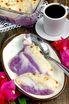 a piece of cake on a plate next to a cup of coffee and pink flowers