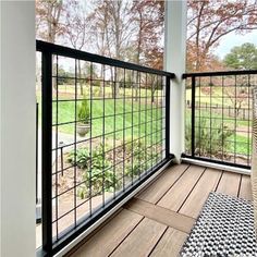 a balcony with wood flooring and black iron railings, overlooking a grassy field