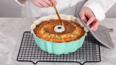 a person cutting into a bundt cake on top of a cooling rack with a spatula