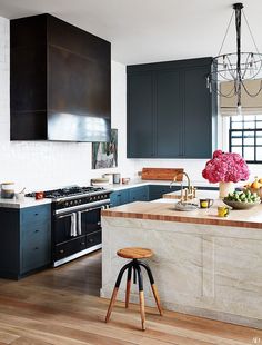 a kitchen with blue cabinets and an island in front of a stove top oven that has fruit on it