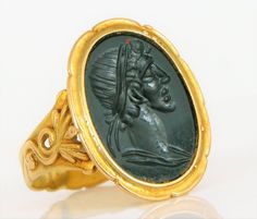 an old gold ring with a black stone in the middle and a head on it