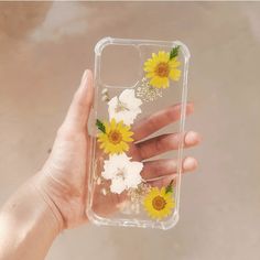 a hand holding a clear phone case with yellow and white flowers on the inside of it