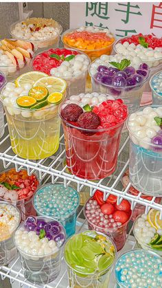 several cups filled with different types of desserts on a metal rack in front of a sign