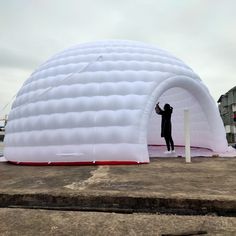 an inflatable white tent with a man standing on it next to a pole