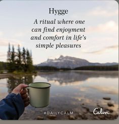 a person holding a cup in their hand with the quote hygge, a ritual where one can find employment and comfort in life's simple pleasure