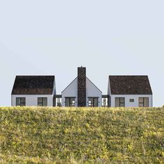 two white houses sitting on top of a lush green hillside