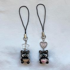 two black and white cats with hearts on their eyes are hanging from a cord that is attached to a lanyard