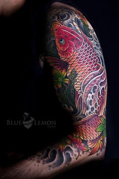 a man's arm with tattoos on it and a fish in the middle of his arm