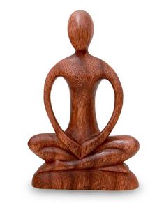 a wooden statue of a person sitting in a yoga position with their hands together and facing the opposite direction